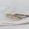 Zu sehen sind zwei filigrane Ringe aus Weißgold und Roségold mit einer natürlichen, rohen Oberfläche. Ab und zu funkeln Diamanten auf den Ringen. Diese können toll als Beisteckring zu Trauringen kombiniert werden