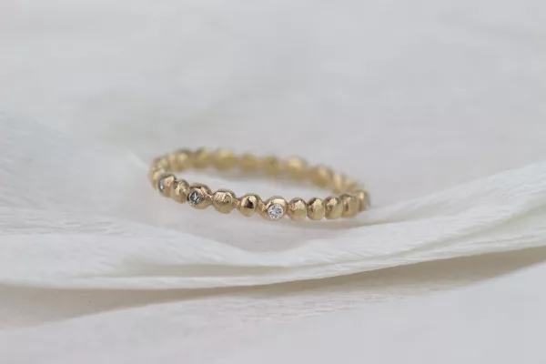 Filigraner Damenring aus Roségold mit einer natürlichen, rohen Oberfläche. Einzelne Diamanten funkeln subtil auf dem Ring. Sieht wundervoll als Beisteckring zu schlichten Eheringen aus.