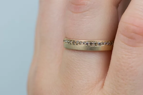 Einzigartiger Ehering aus leicht mattiertem Roségold. Der Damenring ist mit einem faszinierenden Wellenmuster aus funkelnden braunen Diamanten versehen.