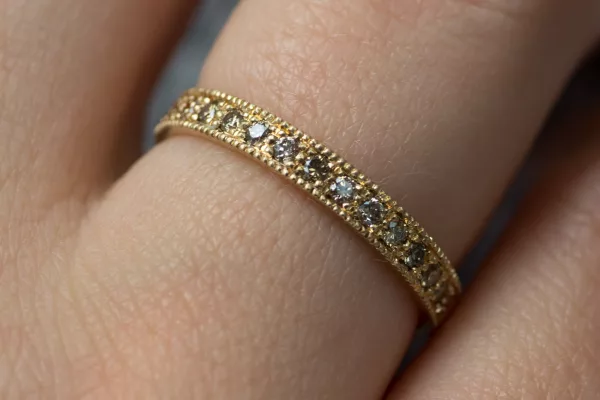 Tragebild eines Eheringes in Roségold. Der Damenring besticht durch sein Vintage-Design mit den vielen braunen Diamanten.