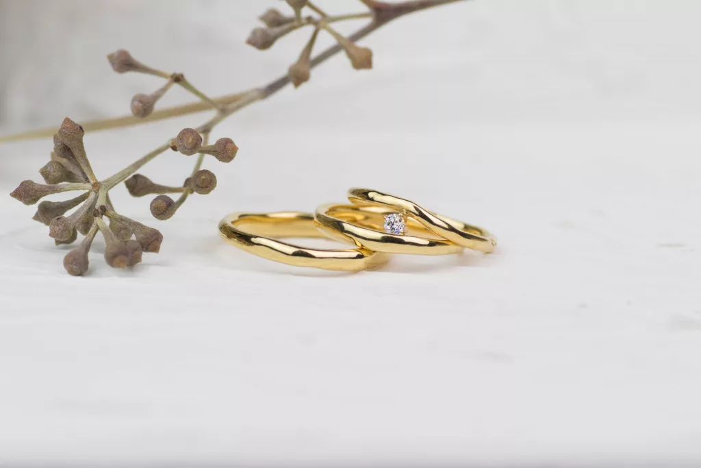 Goldene Eheringe aus 750er Gold mit polierter und abgerundeter Oberfläche. Die Form der Ringe ist natürlich und organisch.