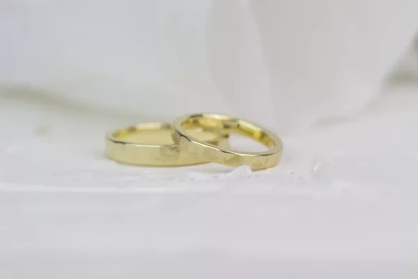 Im Bild zu sehen sind Eheringe aus 585er Gelbgold mit einem groben Hammerschlag. Die Ringe erschienen glänzend.