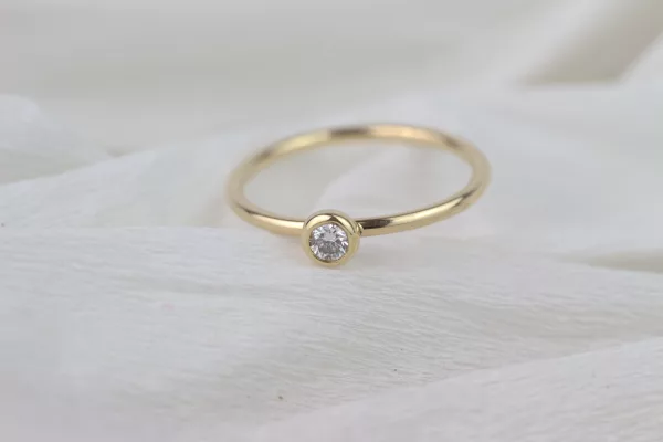 Eleganter und zeitloser Verlobungsring aus edlem 750er Gelbgold, poliert und strahlend. Der Diamant im Brillantschliff in einer sicheren Zargenfassung verleiht ihm zeitlose Schönheit.