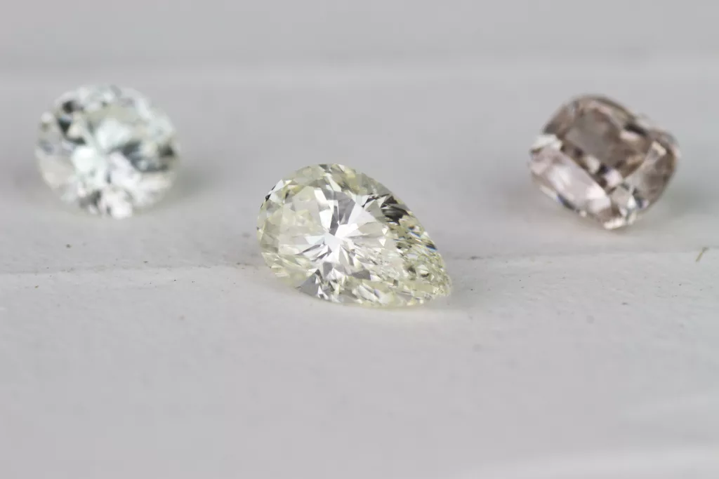Drei Diamanten in verschiedenen Schliffen - brauner Kissenschliff, leicht gelblicher Diamant in Tropfenform, strahlender weißer Brillant - perfekt für individuelle Eheringe.